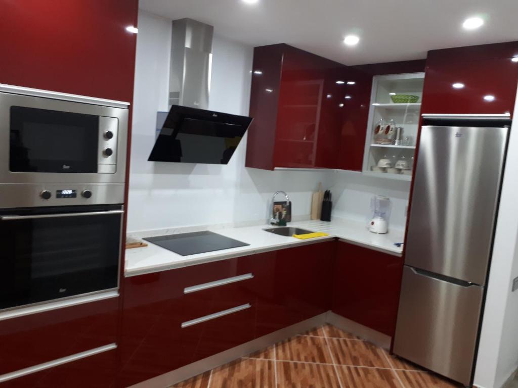 コラレホにあるAppartamento Corralejoのキッチン(赤いキャビネット、ステンレス製の冷蔵庫付)