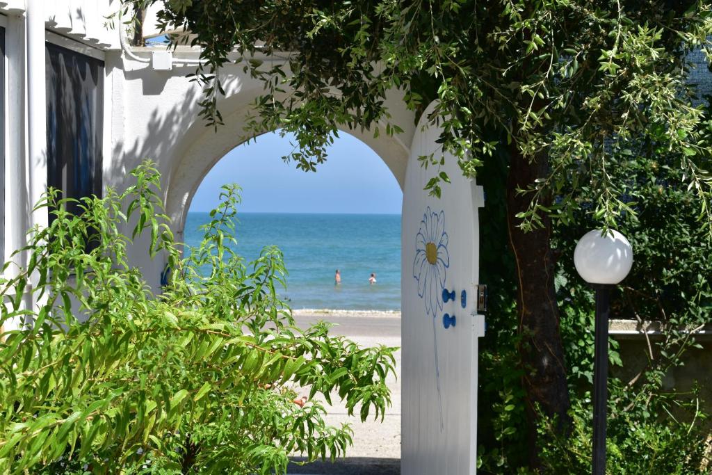 um arco que leva à praia com pessoas nadando no oceano em La Margherita Case Vacanze em Rodi Garganico