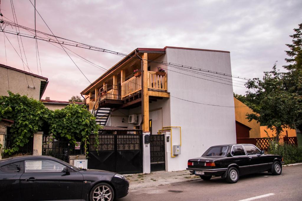 two cars parked in front of a house with a balcony at Casa Faleza in Constanţa