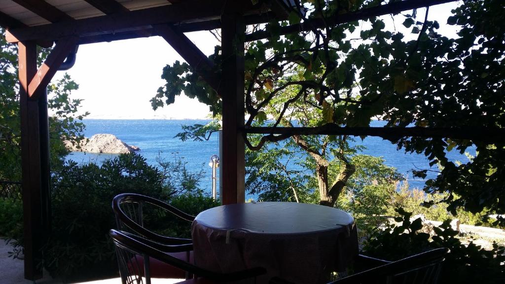 una mesa y sillas en un porche con vistas al océano en Holiday Home Rudelic, en Lukovo Šugarje