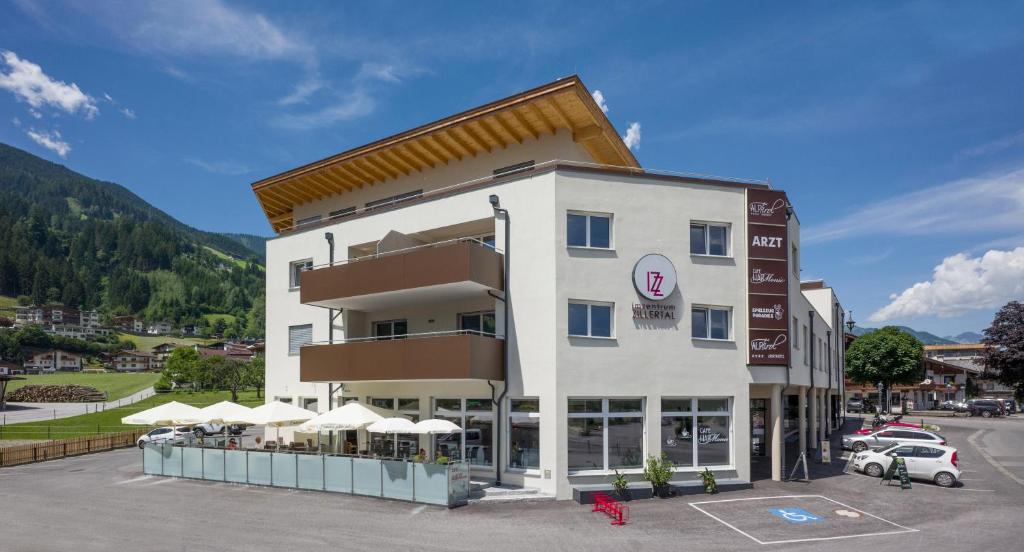 a hotel in a parking lot with a building at Aparthotel AlpTirol in Kaltenbach