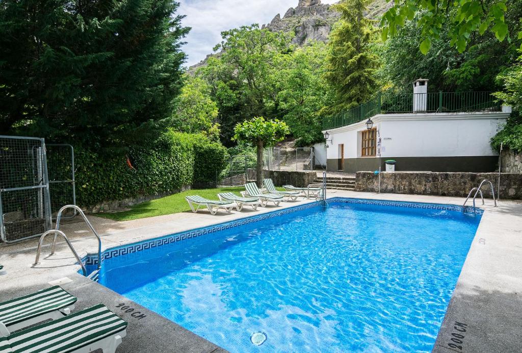 einen Pool mit Stühlen und ein Haus in der Unterkunft Villa Turística de Cazorla in Cazorla