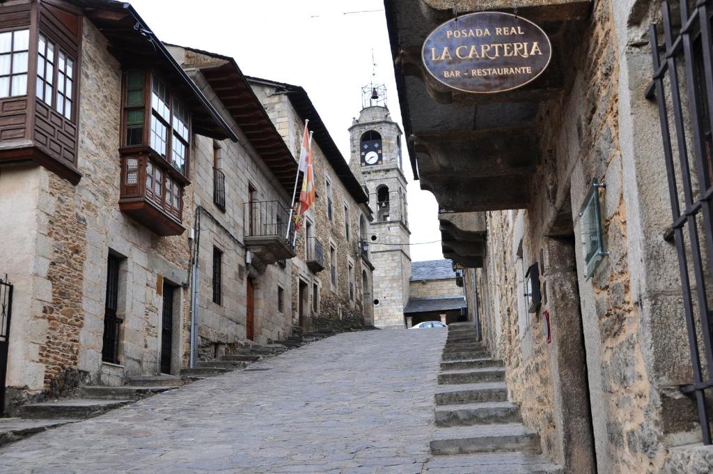 an alley with a building with a clock tower at Posada Real La Carteria in Puebla de Sanabria