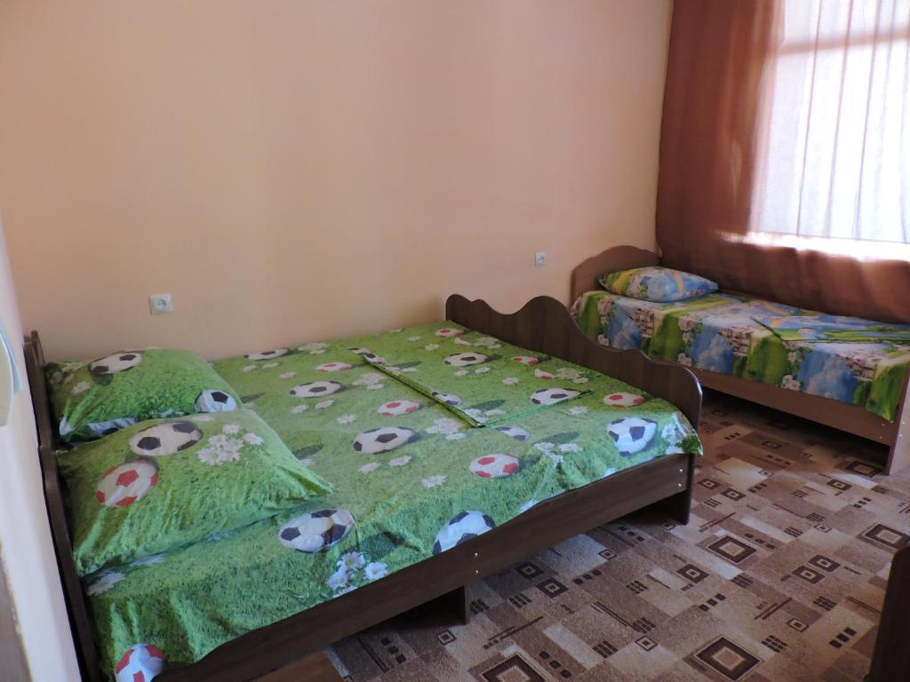 a bedroom with two beds with a green comforter with cows at Guesthouse U Moti in Novy Afon