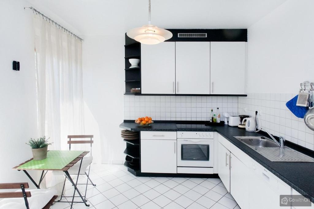 eine Küche mit weißen Schränken, einer Spüle und einem Tisch in der Unterkunft Berlin Center in Berlin