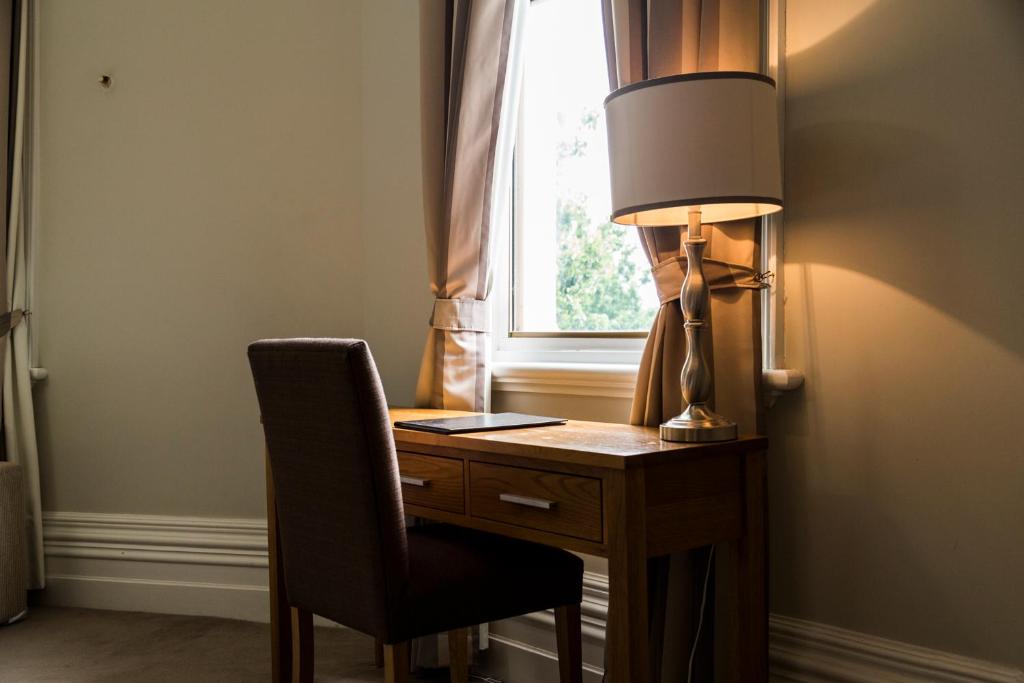 a desk with a lamp and a chair next to a window at Simmers Serviced Apartments in Williamstown