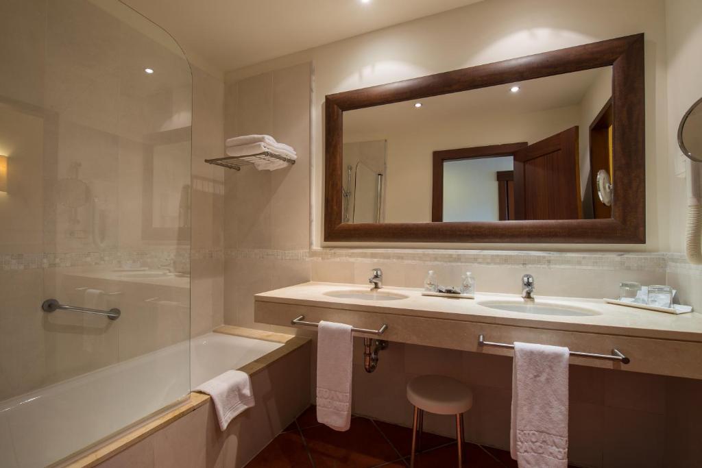 a bathroom with a sink and a tub and a mirror at Puerto Antilla Grand Hotel in Islantilla
