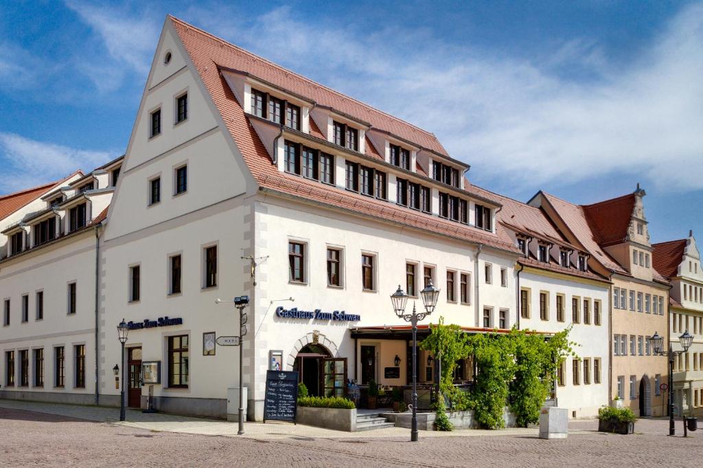 ein großes weißes Gebäude mit rotem Dach in der Unterkunft Gasthaus Zum Schwan in Oschatz