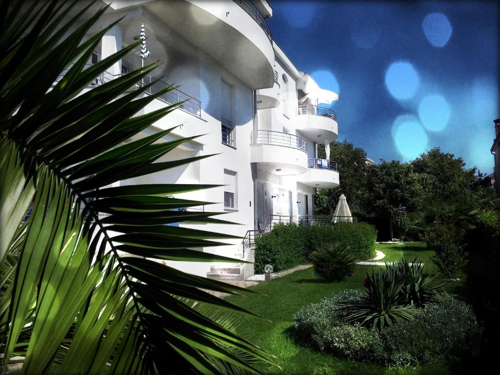a white building with a palm tree in front of it at Luxury Apartments Zana in Zadar