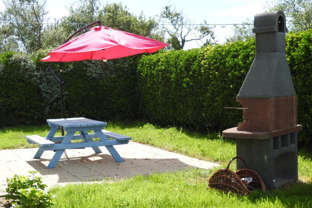 a picnic table with a red umbrella and a grill at Chambres d'Hotes Elvire et Laurent Barbey in Sainte-Marie-du-Mont