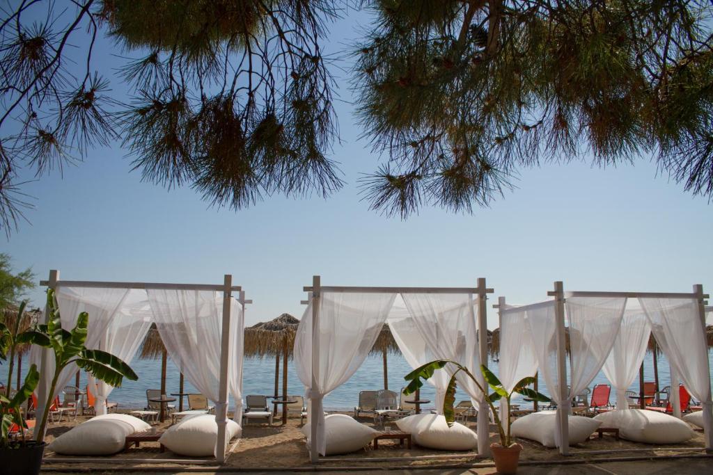 een rij witte tenten op een strand met de oceaan bij Hotel Hellas in Oud Epidauros