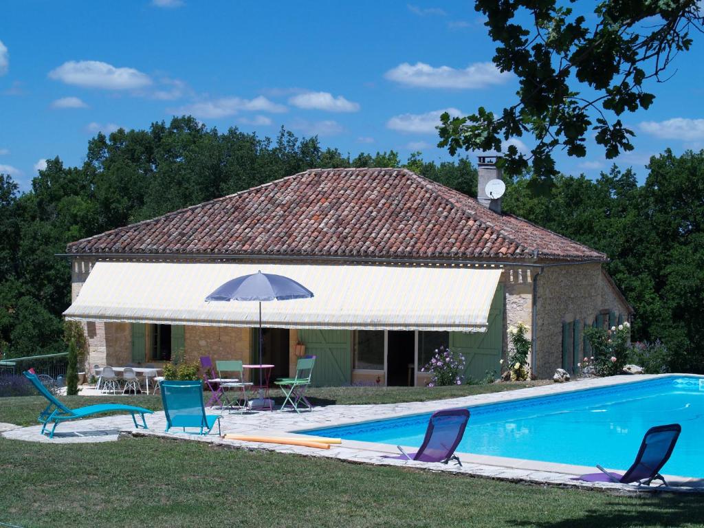 ein Haus mit einem Pool mit Stühlen und einem Sonnenschirm in der Unterkunft A Labourdette in Marsolan