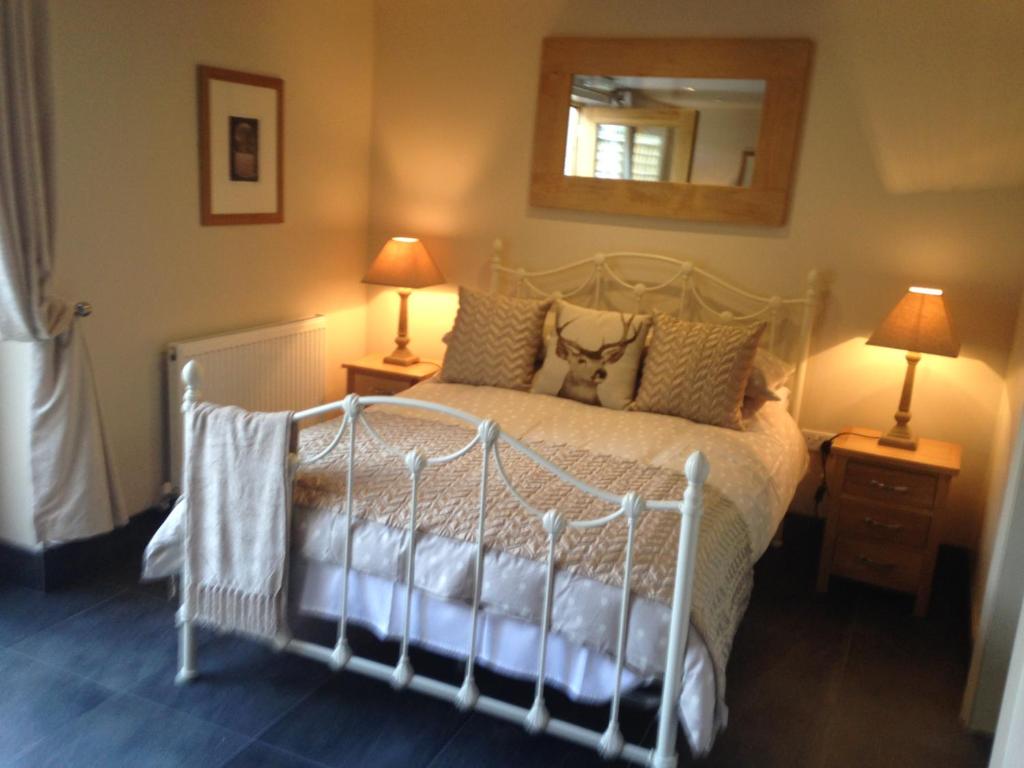 a bedroom with a white bed with two lamps and a mirror at The Queens in Ludlow