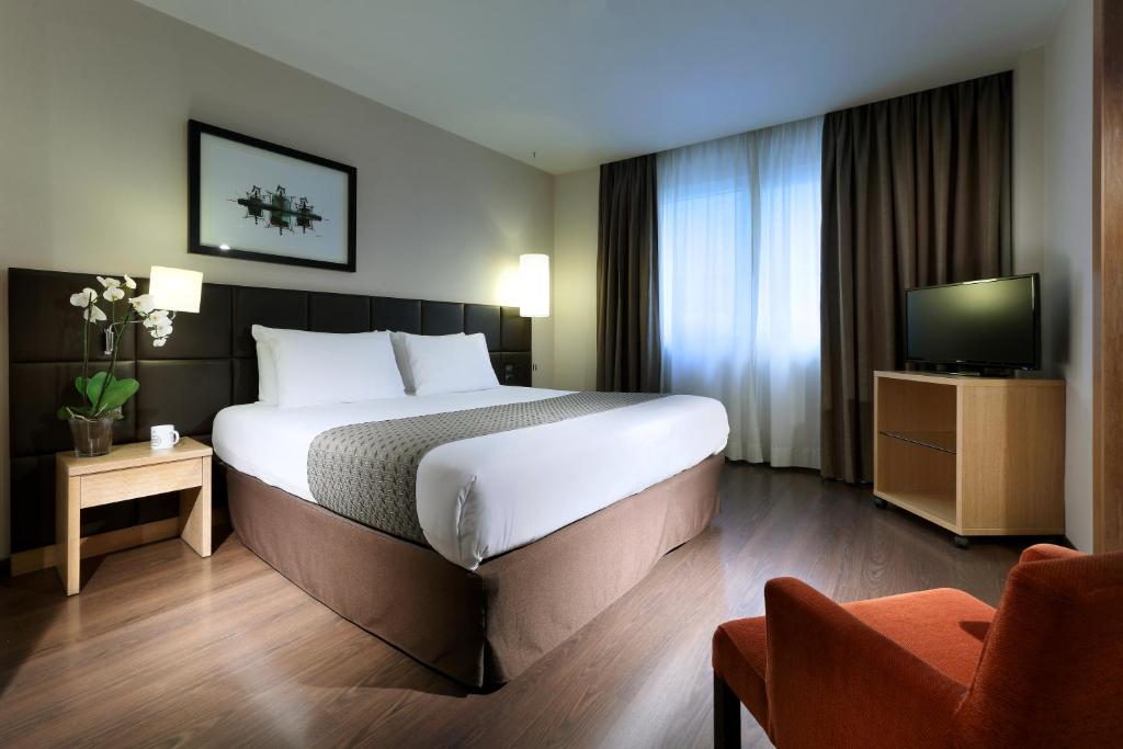 a hotel room with a bed, desk, chair and lamp at Eurostars Lucentum in Alicante