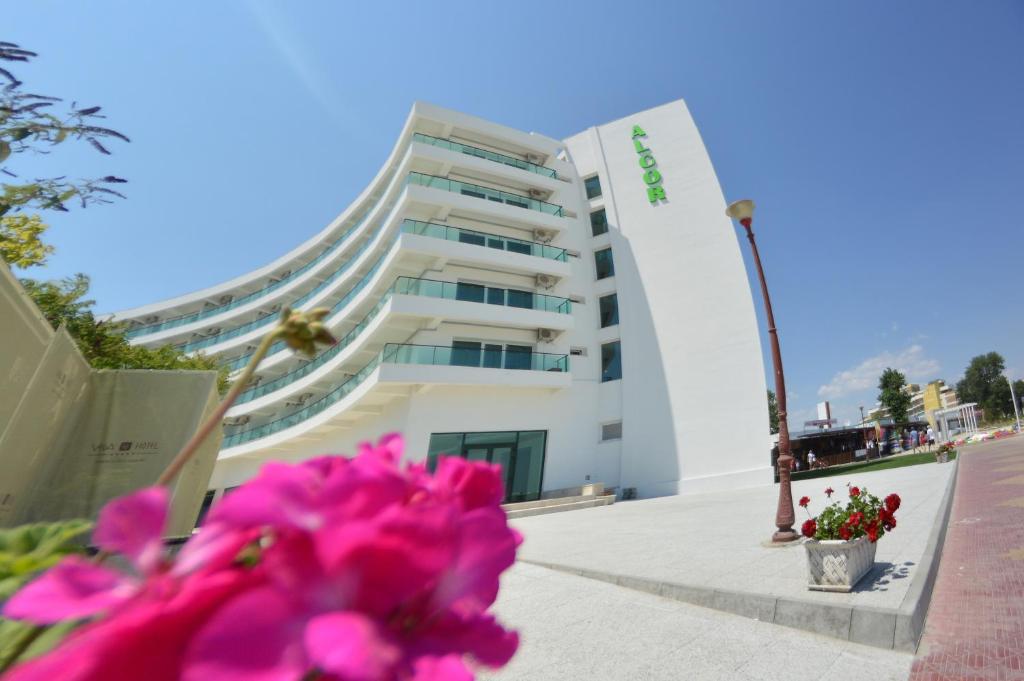 a building with pink flowers in front of it at Alcor Beach Hotel in Mamaia