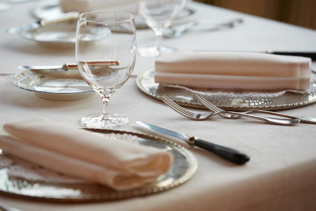 una mesa con platos, vasos y cubiertos en Hotel Alle Ciaspole, en Fondo