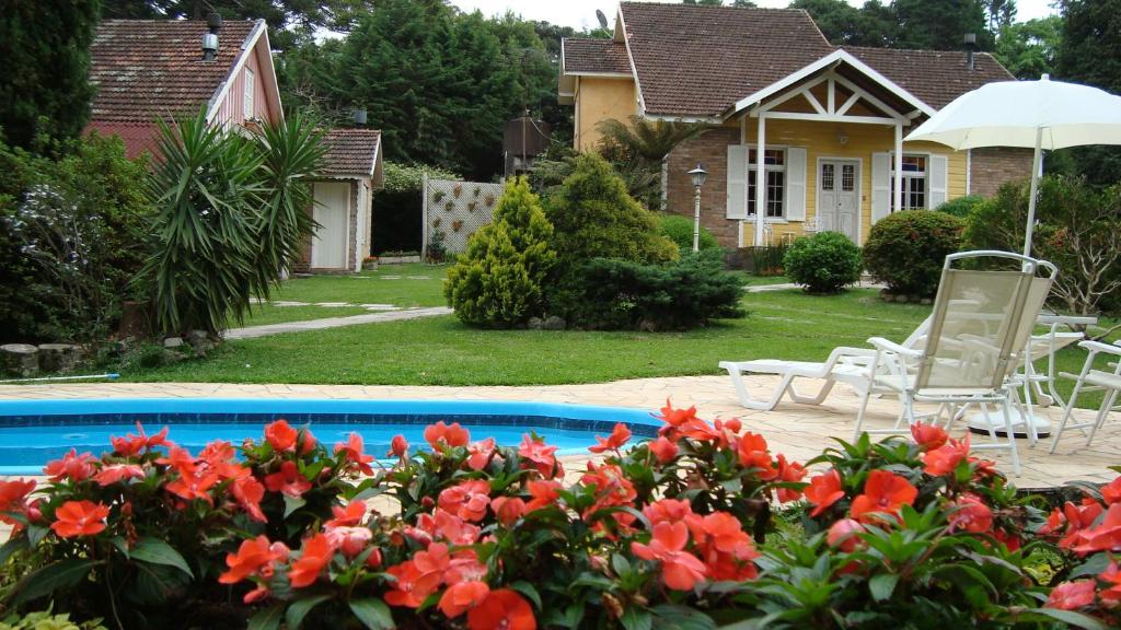 a house with a swimming pool with red flowers at Pousada Aldeia dos Sonhos in Canela