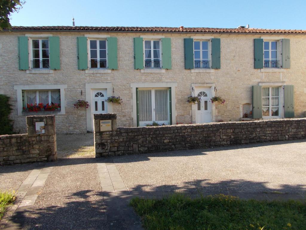Casa de ladrillo con persianas verdes y pared de piedra en Le Petit Bijou en Saint-Fraigne