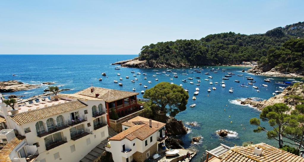 a large body of water with houses and boats at Hotel Aigua Blava in Begur