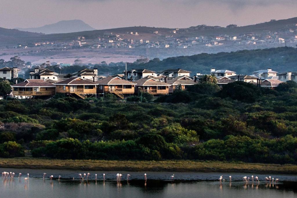 un grupo de casas en una colina junto a un cuerpo de agua en Dibiki Holiday Resort, en Hartenbos