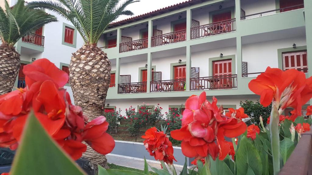 um hotel com flores vermelhas e palmeiras em The Flower Of Monemvasia Hotel em Monemvasia