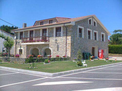 a large stone house on the side of a street at Posada Playa de Langre in Langre