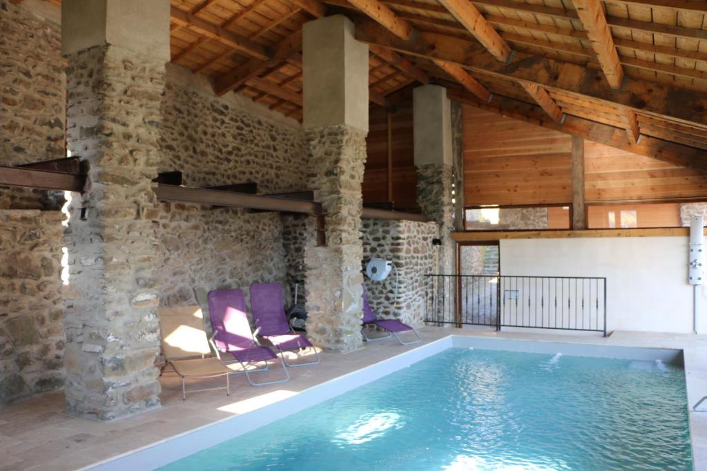 uma piscina num quarto com uma parede de pedra e tectos de madeira em Domaine de Chabanet em Privas