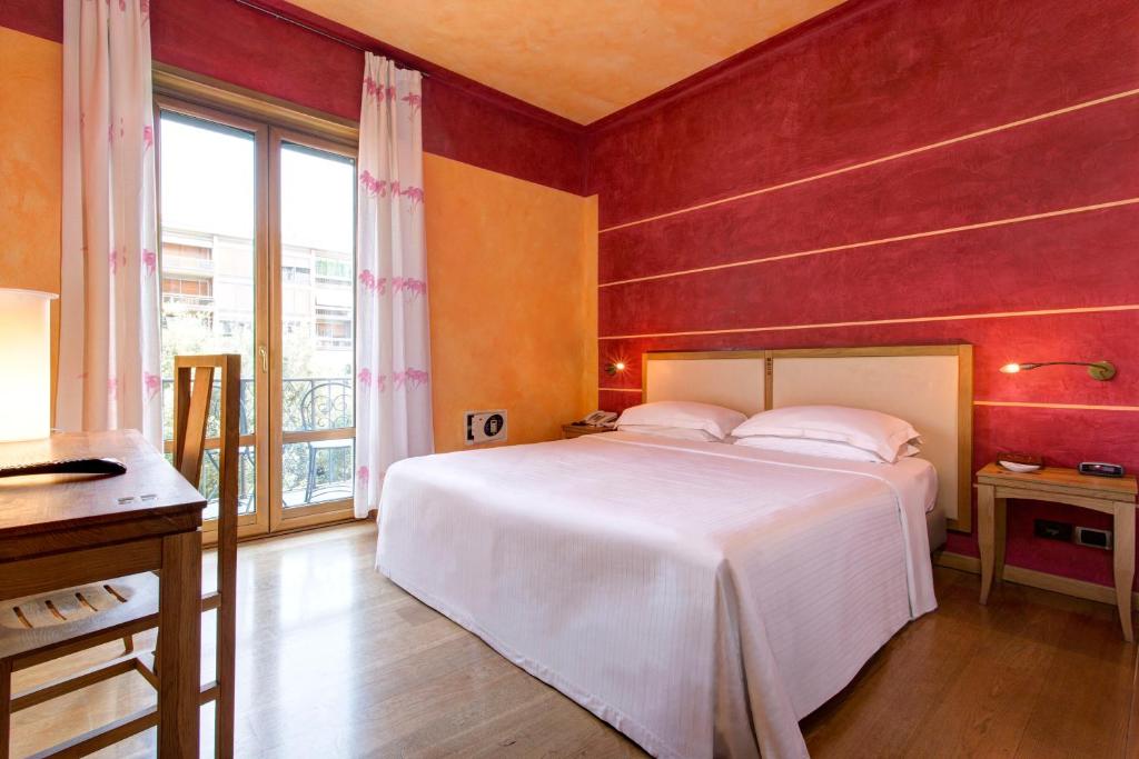 una camera con un letto bianco e una parete rossa di Appartamenti Porta Nuova 80 a Verona