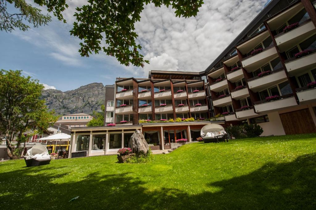 a hotel with a green lawn in front of a building at Hotel Quellenhof Leukerbad in Leukerbad