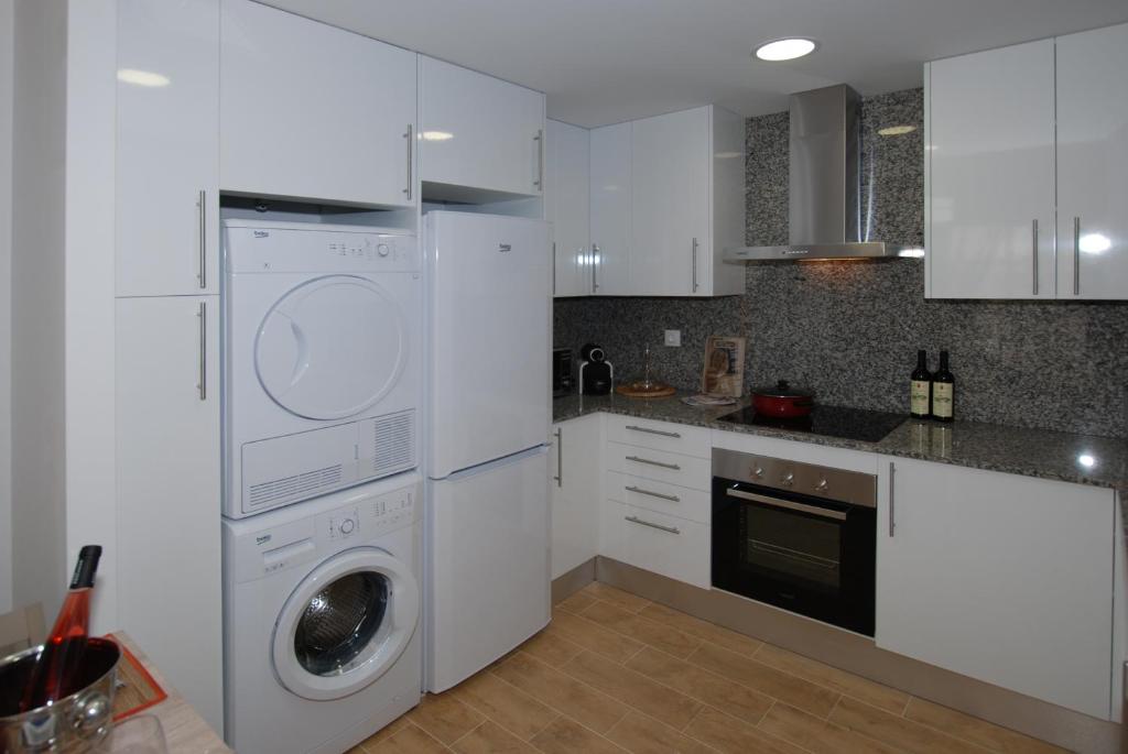 a kitchen with white cabinets and a washer and dryer at Apartments Gran VP in Cambrils