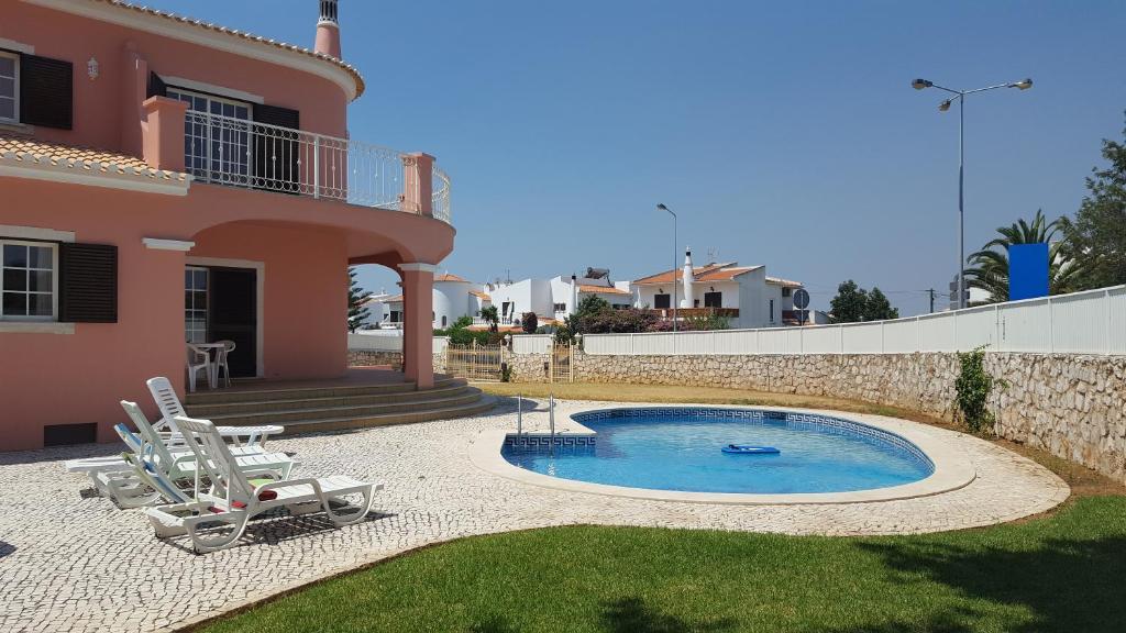 a villa with a swimming pool in front of a house at Saraiva's Guest House in Lagos