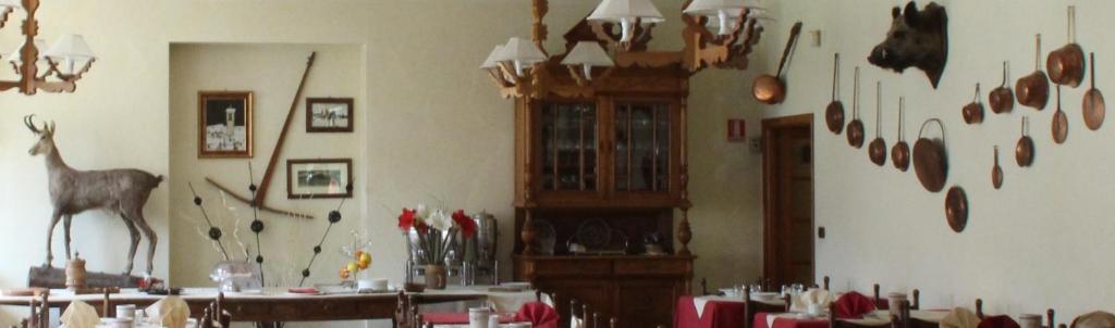 a dining room with tables and a room with animal heads on the wall at Hotel Banchetta in Sestriere