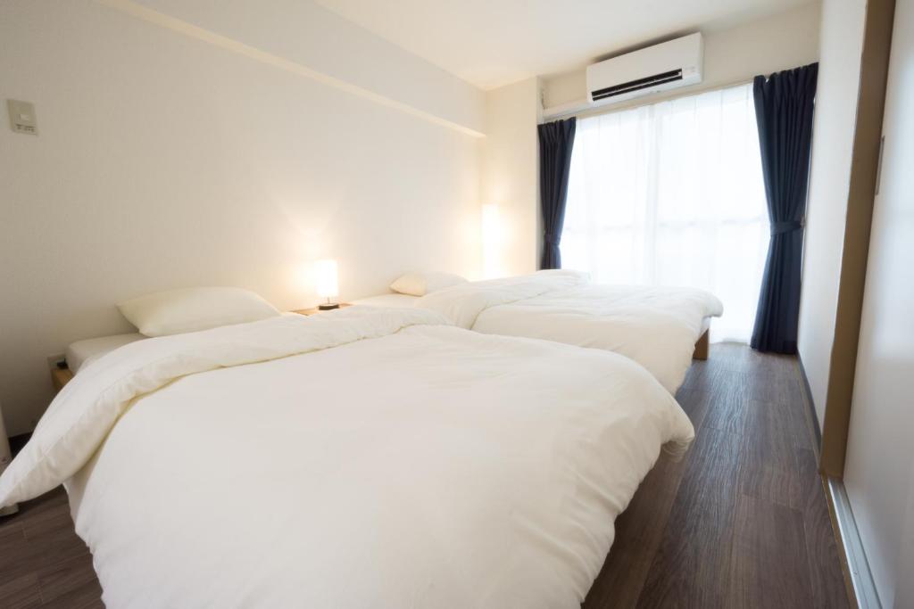 東京にあるGOEN inn Tokyoの窓付きの客室で、白いベッド2台が備わります。