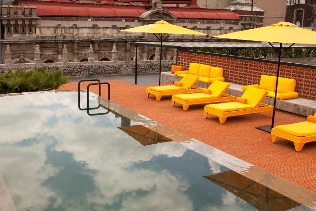 - un groupe de chaises et de parasols jaunes dans une piscine dans l'établissement Downtown Mexico, a Member of Design Hotels, à Mexico