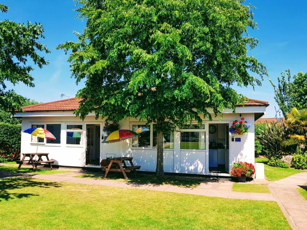 a cottage with a picnic table and a tree at Dawlish Warren Holidays in Dawlish