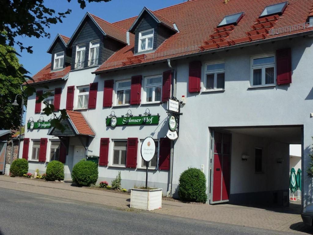un grand bâtiment blanc avec volets rouges dans l'établissement Landhotel Solmser Hof, à Echzell