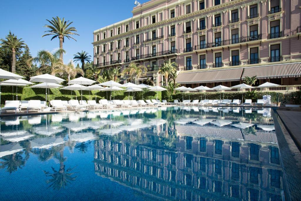 a swimming pool in front of a building with umbrellas at Hotel Royal-Riviera in Saint-Jean-Cap-Ferrat