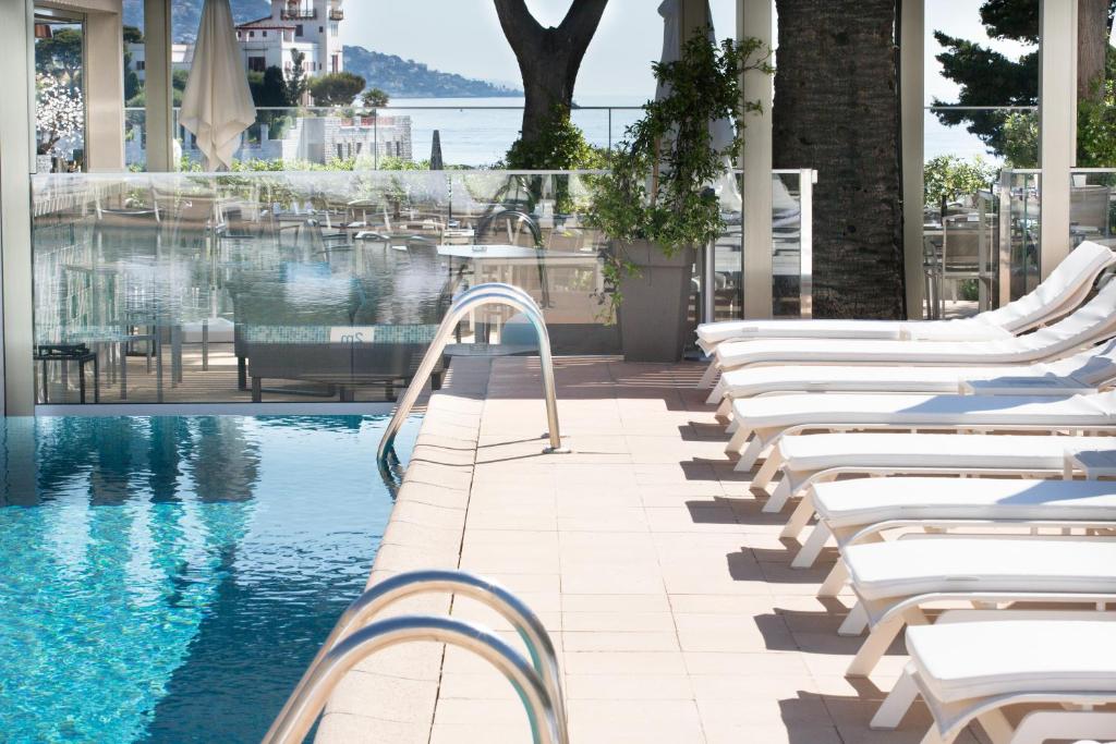 a swimming pool with white lounge chairs next to a building at Hotel Royal-Riviera in Saint-Jean-Cap-Ferrat