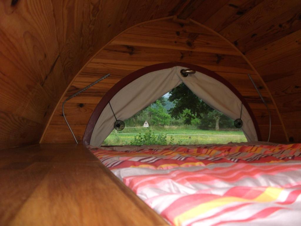 a bed in a tent with a window at Les Cahutes d'Olt in Saint-Laurent-dʼOlt