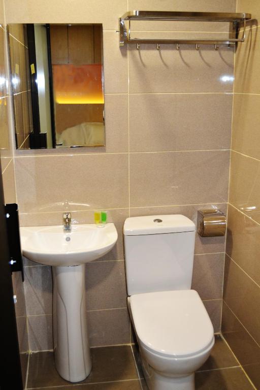 A compact bathroom with a pedestal sink, toilet and wall-mounted towel rack.