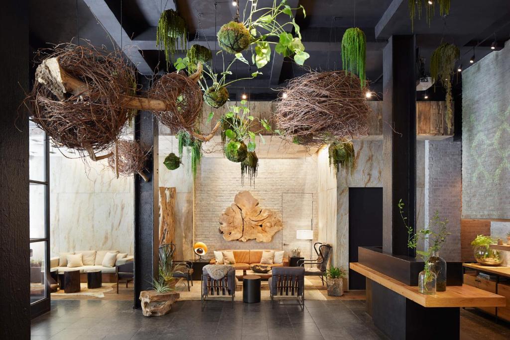 a lobby with a couch and chairs and plants at 1 Hotel Central Park in New York