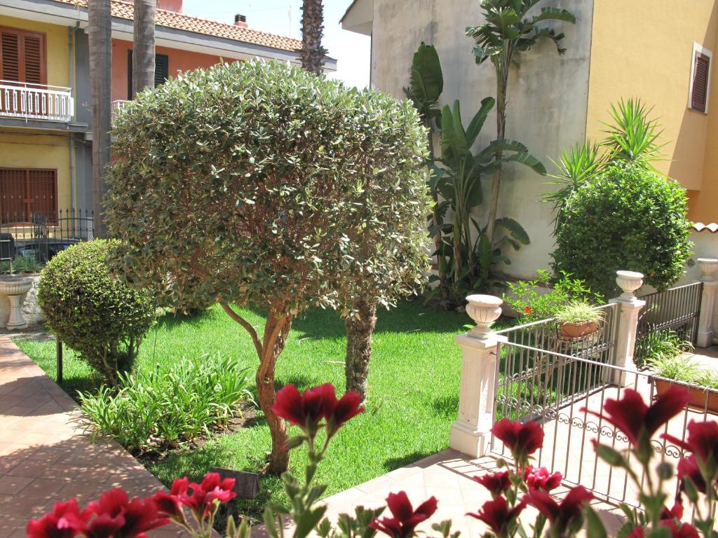 アチレアーレにあるSicily for you Apartmentの小木と赤い花の庭園