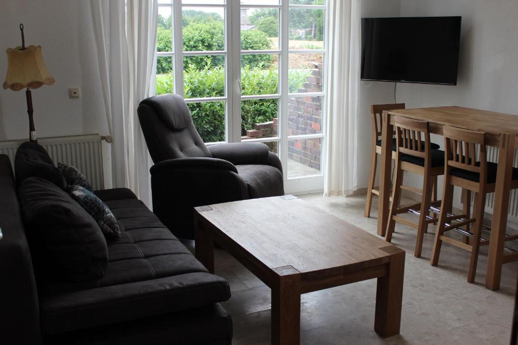 een woonkamer met een bank, stoelen en een tafel bij Ferienhof Frerichs ihr Feriendomizil am Meer in Wangerland