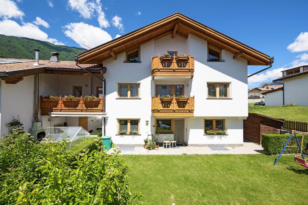 ein weißes Haus mit Holzbalkonen und einem Hof in der Unterkunft Appartement Thanei in Burgeis