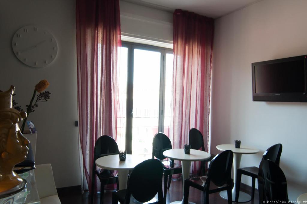 Habitación con mesas, sillas y ventana grande. en Eh13 Luxury Accommodation, en Catania