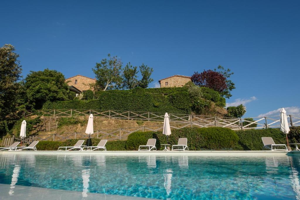 a swimming pool with chairs and umbrellas at Borgo Amarrante in Montaione