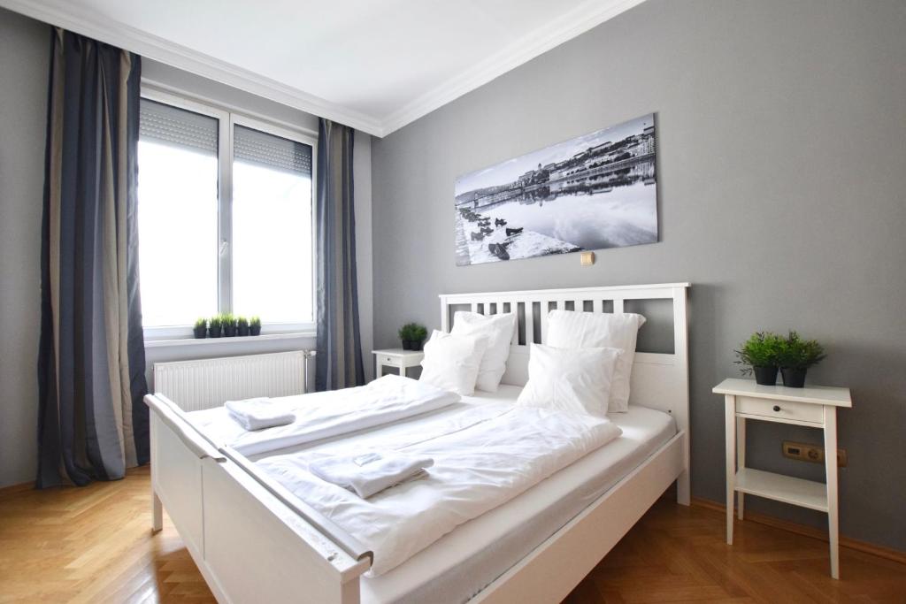 Cette chambre comprend un lit blanc et une grande fenêtre. dans l'établissement Luxury Apartment by Hi5 - Lovag Suites, à Budapest