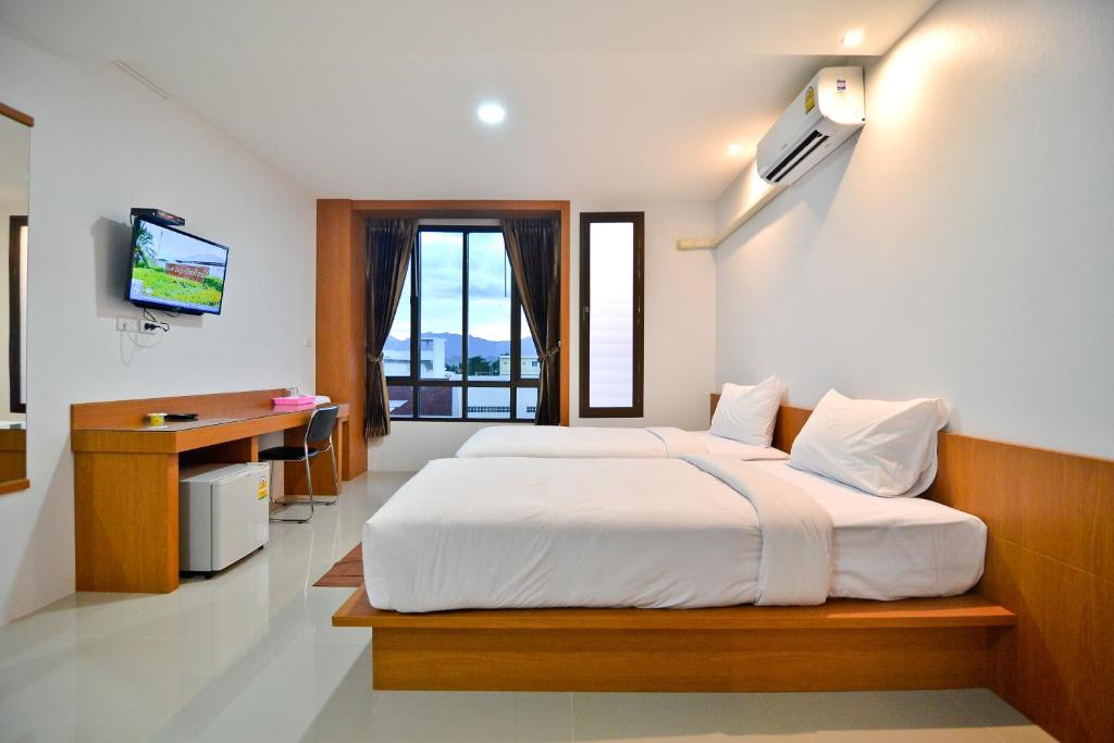 Sabuy Best Hotel Phayao في فاياو: غرفة نوم بسرير ومكتب وتلفزيون