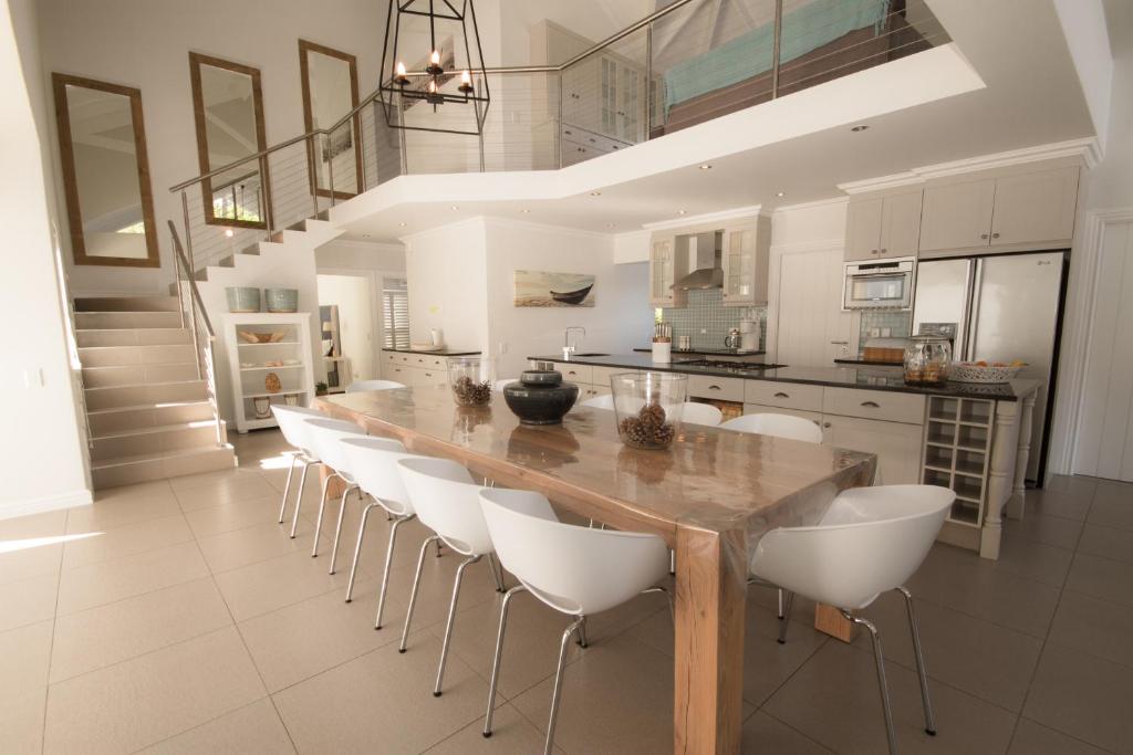 a kitchen with a long wooden table and white chairs at Stableford Beach House Plett in Plettenberg Bay