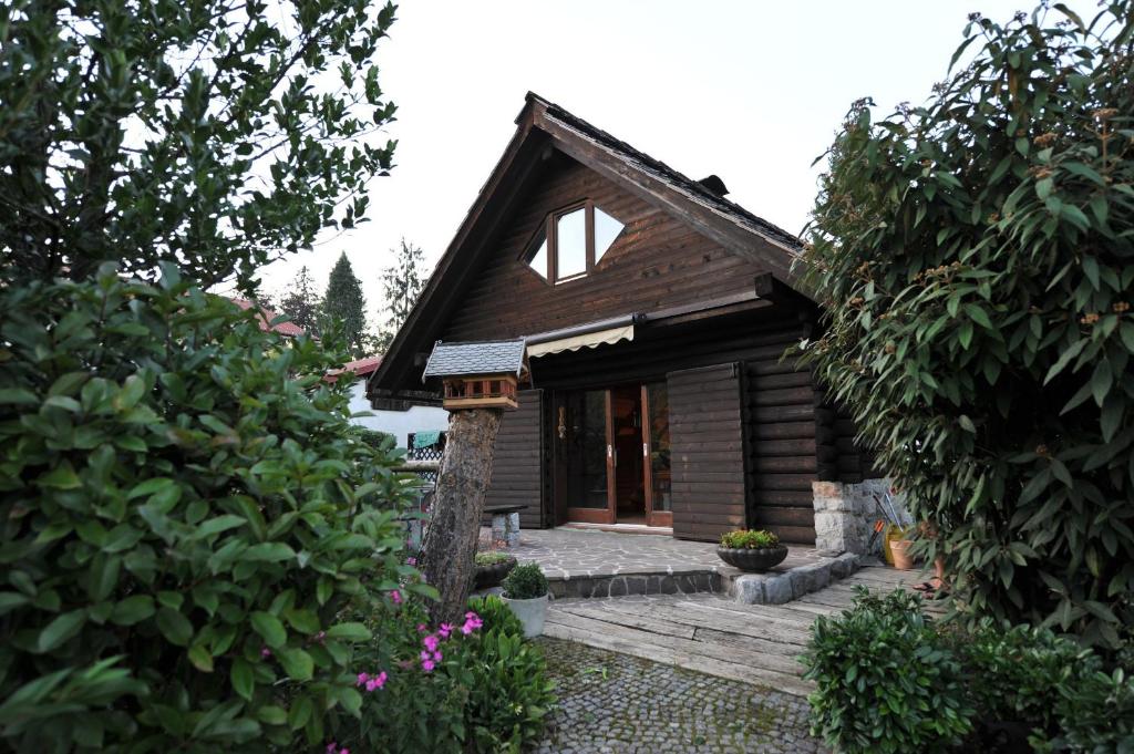 a small wooden house with a porch and some bushes at Alice Chalet Bled in Bled